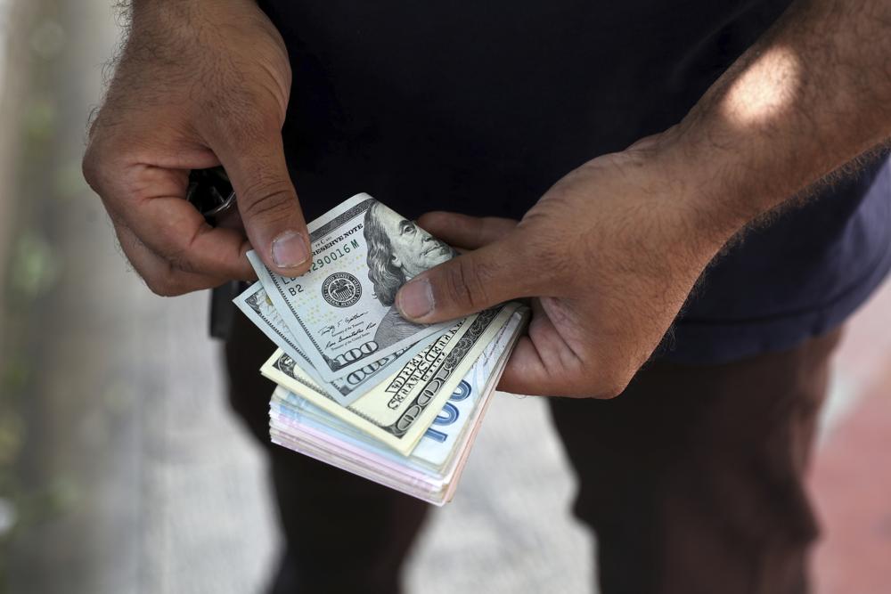 A street money exchanger poses for a photo without showing his face as he counts foreign banknotes in Ferdowsi street, Tehran's go-to venue for foreign currency exchange, Iran, Sunday, June 12, 2022. Iran's currency Sunday dropped to its lowest value ever as talks to revive the country's tattered nuclear deal with world powers remained deadlocked. (AP Photo/Vahid Salemi)