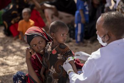 Un enfermero mide el brazo de Nimo Abdi, quien padece diarrea y vómitos y recibe tratamiento por desnutrición, mientras la sostiene su madre Shamis Dhire en una clínica móvil de UNICEF en la aldea de Barare, región somalí de Etiopía, 20 de enero de 2022. La sequía en el Cuerno de África amenaza millones de vidas.  (Mulugeta Ayene/UNICEF via AP)