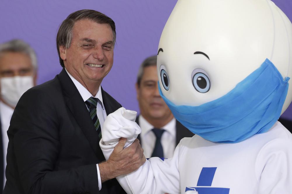 FILE - Brazilian President Jair Bolsonaro poses for photos with the mascot of his nation's vaccination campaign, named Ze Gotinha, or Joseph Droplet, during a ceremony to present the National Vaccination Plan Against COVID-19 at Planalto presidential palace in Brasilia, Brazil, Dec. 16, 2020. Brazil's government started taking an online public survey on Dec. 24, 2021 to inform their decisions about whether and how to vaccinate children against the coronavirus. (AP Photo/Eraldo Peres, File)