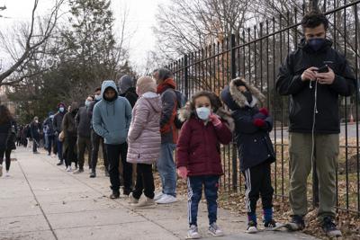 Unos niños esperan con sus padres en una fila para pruebas diagnósticas de coronavirus, el martes 21 de diciembre de 2021, en Washington. (AP Foto/Jacquelyn Martin)