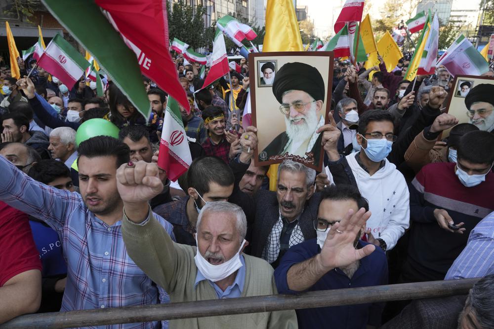 Demonstrators chant slogans as one of them holds up a poster of Iranian Supreme Leader Ayatollah Ali Khamenei during a demonstration in front of the former U.S. Embassy in Tehran, Iran, Friday, Nov. 4, 2022. Iran on Friday marked the 1979 takeover of the U.S. Embassy in Tehran as its theocracy faces nationwide protests after the death of a 22-year-old woman earlier arrested by the country's morality police. (AP Photo/Vahid Salemi)