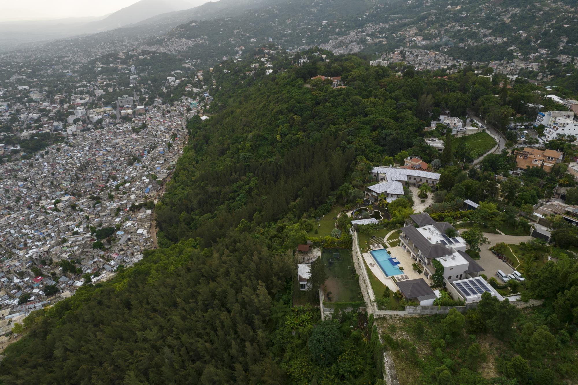 Swathes of green separate the densely populated Jalousie neighborhood from the wealthy suburb Petion-Ville, in Port-au-Prince, Haiti, Monday, Oct. 4, 2021. Some of Haiti’s wealthy elite can trace roots to ancestors who came to the country generations ago and built fortunes.  Today there is a constant struggle to keep their business going in the face of threats and extortion by the gangs that rule a country where government has ceased to function. (AP Photo/Rodrigo Abd)