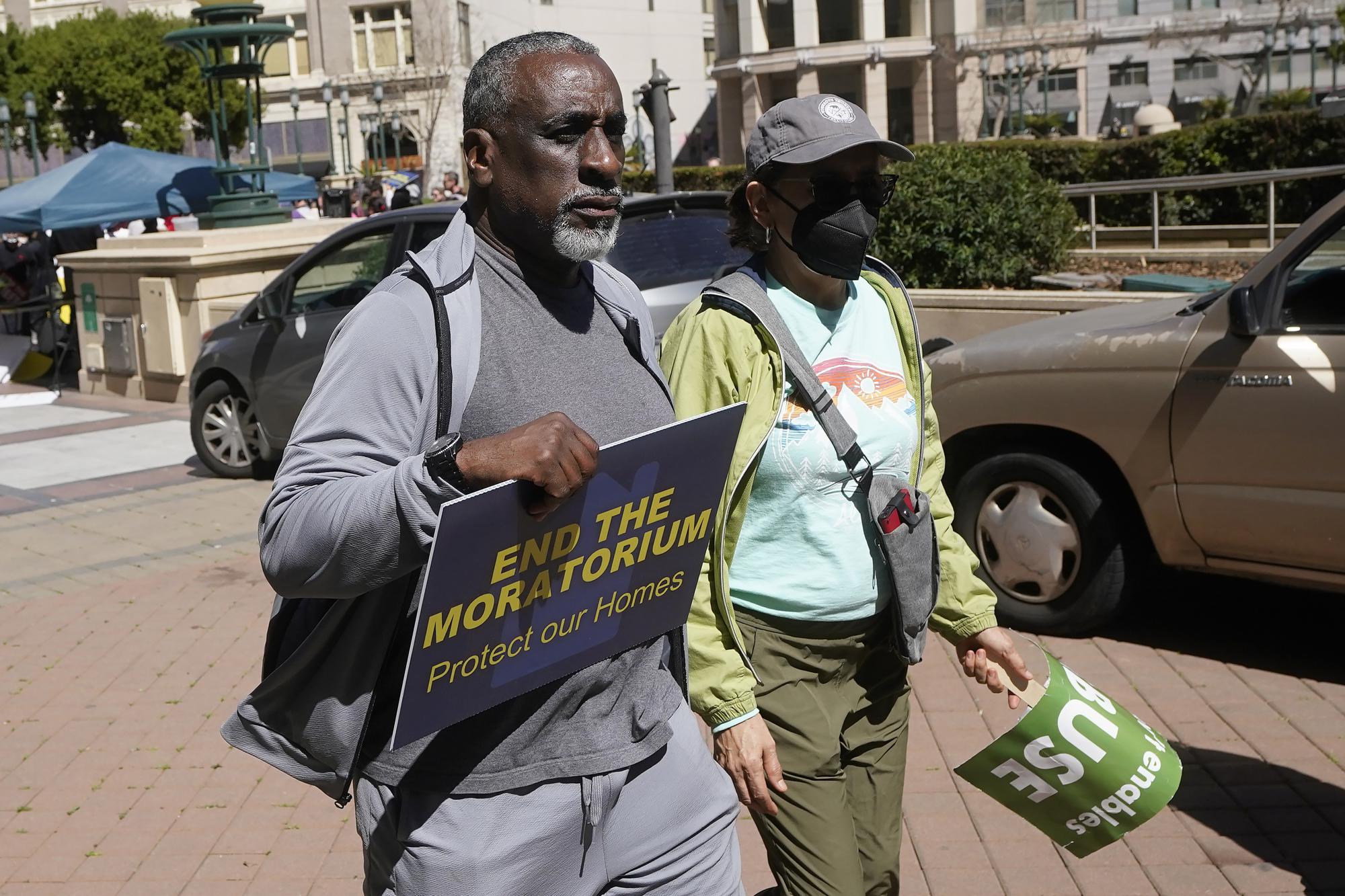 John Williams, left, walks leaves a rally calling for an end to the eviction moratorium before a special community and economic development committee by the Oakland City Council at City Hall in Oakland, Calif., Tuesday, April 11, 2023. Some landlords have gone without rental income for more than three years after Oakland, California approved an eviction moratorium in March 2020. (AP Photo/Jeff Chiu)
