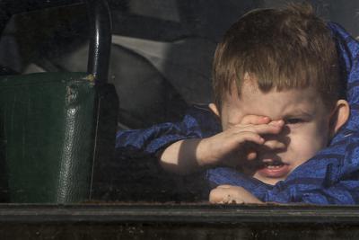 Un niño que espera a ser evacuado a Rusia mira a través de la ventana de un autobús, en Donetsk, un terrotorio del este de Ucrania controlado por separatistas prorrusos, el 19 de febrero de 2022. (AP Foto/Alexei Alexandrov)