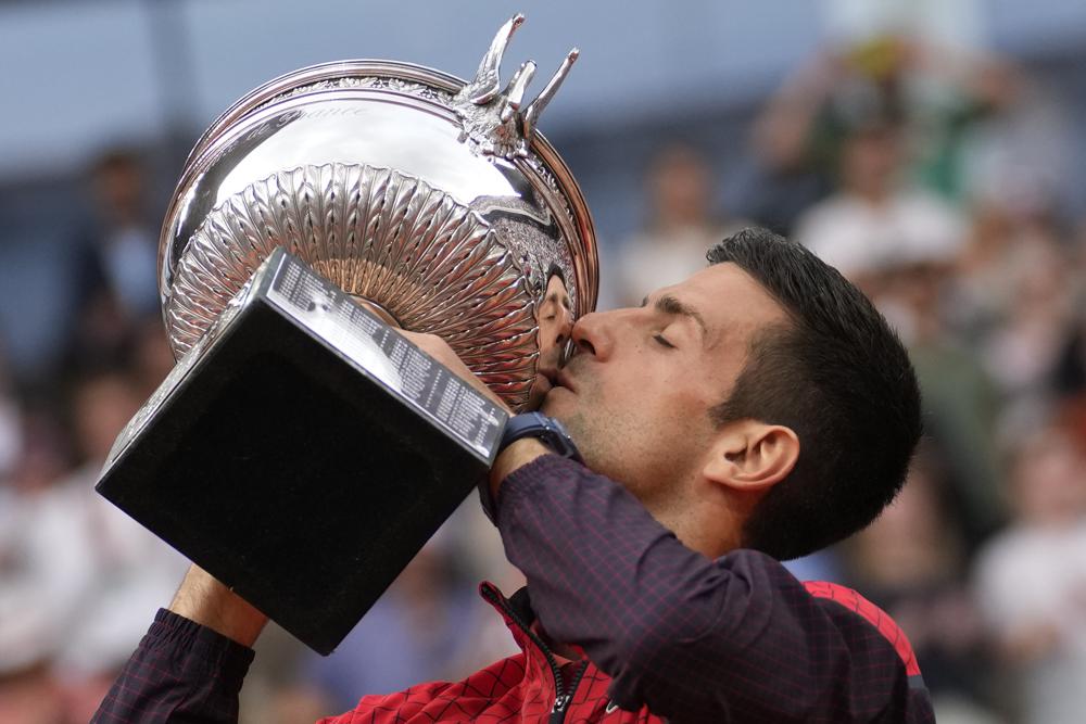 Serbia's Novak Djokovic kisses the trophy as he celebrates winning the men's singles final match of the French Open tennis tournament against Norway's Casper Ruud in three sets, 7-6, (7-1), 6-3, 7-5, at the Roland Garros stadium in Paris, Sunday, June 11, 2023. Djokovic won his record 23rd Grand Slam singles title, breaking a tie with Rafael Nadal for the most by a man. (AP Photo/Christophe Ena)