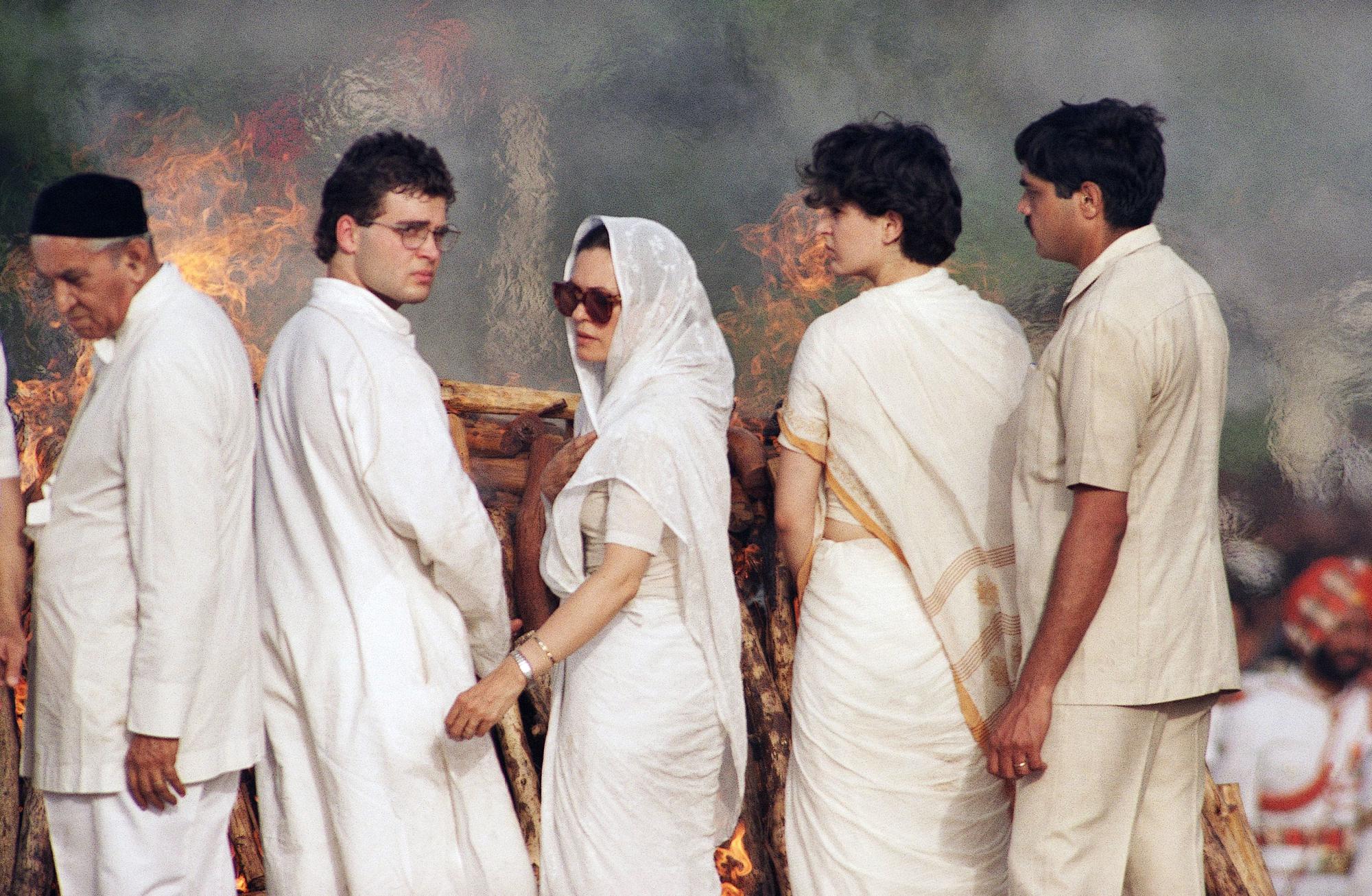 ARQUIVO - A esposa de Rajiv Gandhi, Sonia, centro, e seus dois filhos, Rahul e Priyanka, olham para trás da pira em chamas depois que o corpo do ex-primeiro-ministro indiano foi incendiado durante seu funeral em Nova Delhi, sexta-feira, 24 de maio de 1991 Gandhi foi morto por um homem-bomba do Sri Lanka em um comício eleitoral em Sriperumbudur, no sul da Índia. (Foto AP/Denis Paquin, Arquivo)