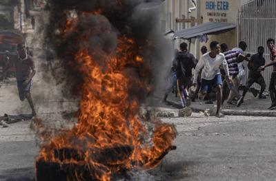 Manifestantes arrojan piedras a la policía durante una protesta por la muerte del periodista Romelo Vilsaint, el domingo 30 de octubre de 2022, en Puerto Príncipe, Haití. (AP Foto/Ramón Espinosa)