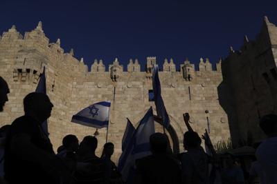 Ultranacionalistas judíos ondean banderas israelíes durante una mrcha al pasar junto a la Puerta de Damasco, fuera de la Ciudad Vieja de Jerusalén, el martes 15 de junio de 2021. (AP Foto/Ariel Schalit)