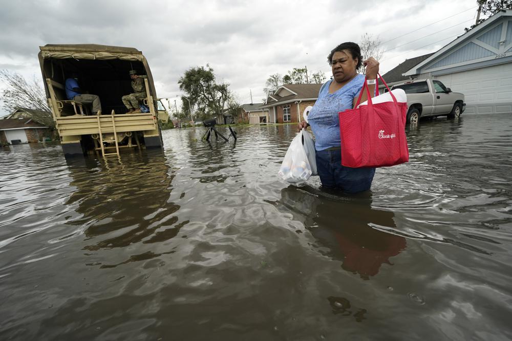 Jerilyn Collins regresa a su destrozada casa con la ayuda de un camión para inundaciones de la Guardia Nacional de Luisiana para recuperar medicamentos para ella y su padre y algunos objetos más, tras ser evacuada luego del paso del huracán Ida, en LaPlace, Luisiana, el 30 de agosto de 2021. (AP Foto/Gerald Herbert)