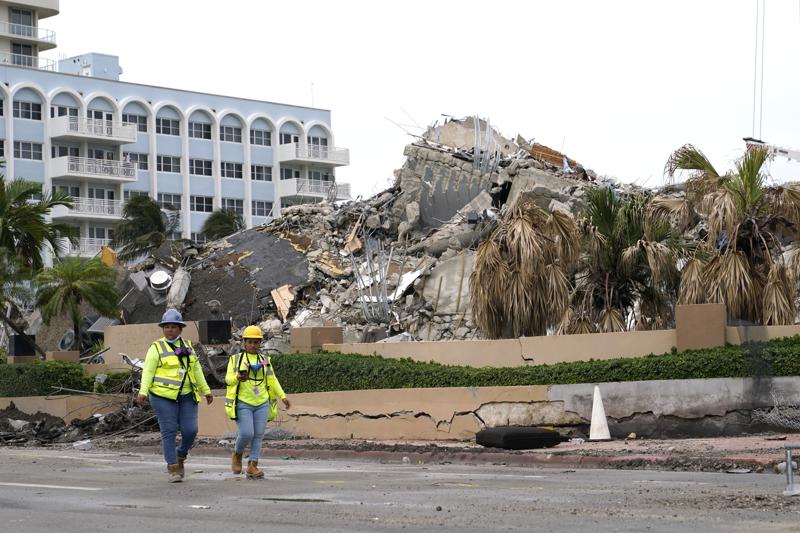 Workers walk past the collapsed and subsequently demolished Champlain Towers South condominium building, Tuesday, July 6, 2021, in Surfside, Fla. (AP Photo/Lynne Sladky)