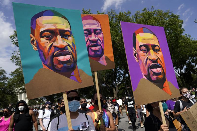 FILE - In this Aug. 28, 2020, file photo, people carry posters with George Floyd on them as they march from the Lincoln Memorial to the Martin Luther King Jr. Memorial in Washington. As the anniversary of George Floyd’s murder approaches, some people say the best way to honor him is for Congress to pass a bill in his name that overhauls policing. (AP Photo/Carolyn Kaster, File)