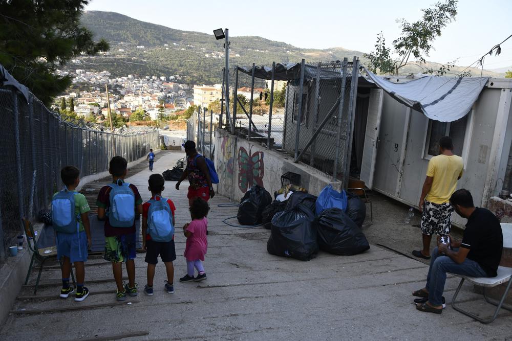 Migrants leave from an overcrowded refugee camp at the port of Vathy on the eastern Aegean island of Samos, Greece, Monday, Sept. 20, 2021. The transfer of all the migrants to the new €43 million ($50 million) closed monitored facility began Monday and be completed by Wednesday. (AP Photo/Michael Svarnias)