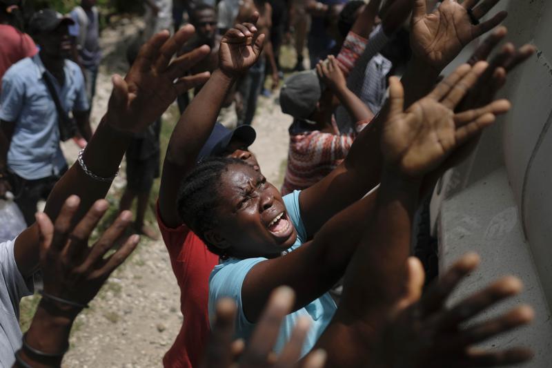 Earthquake victims reach for water being handed out during a food distribution in the Picot neighborhood in Les Cayes, Haiti, Sunday, Aug. 22, 2021, eight days after a 7.2 magnitude earthquake hit the area. (AP Photo/Matias Delacroix)