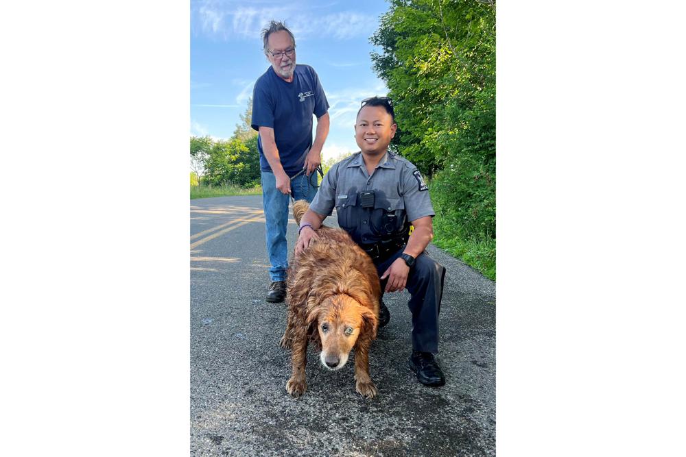 In this image provided by the New York State Police, Trooper Jimmy Rasaphone, right, poses for a photo with 13-year-old golden retriever Lilah, and her owner Rudy Fuehrer, after the trooper rescued her from a culvert pipe in Conklin, NY., on Sunday, June 26, 2022. Rasaphone grabbed a rope and crawled about 15 feet into the pipe, got to the dog and put her collar on her, and pulled the dog to safety with Fuehrer's help. (New York State Police via AP)