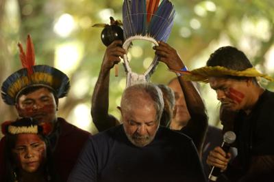 ARCHIVO - El ex presidente de Brasil que se postulaba para la reelección, Luiz Inácio Lula da Silva, recibe un tocado del pueblo indígena Assurini durante una reunión con poblaciones tradicionales de la Amazonía en Belem, estado de Pará, Brasil, el 2 de septiembre de 2022. En un discurso de victoria el domingo 30 de octubre, el presidente electo de Brasil, Lula, prometió revertir un aumento de la deforestación en la selva amazónica. (AP Photo/Raimundo Pacco, Archivo)