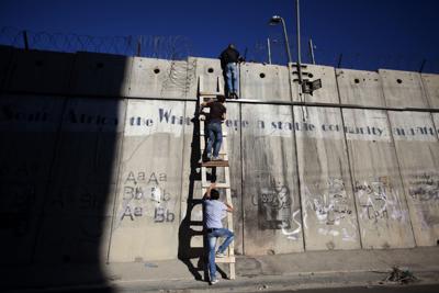 En esta imagen de archivo, palestinos emplean una escalera para escalar el muro de separación con Israel mientras se dirigen a rezar a la mezquita de al-Aqsa, en Jerusalén, durante el mes sagrado musulmán del Ramadán, en Al-Ram, al norte de Jerusalén, el 11 de julio de 2014. (AP Foto/Majdi Mohammed, arcbivo)