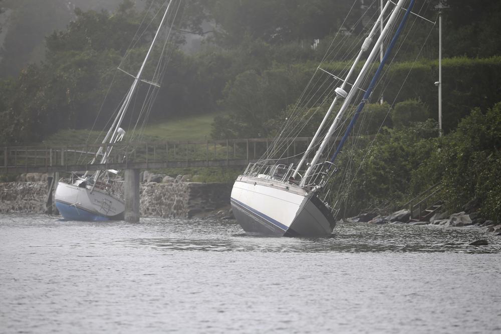 Zwei Segelboote, die sich von ihren Liegeplätzen gelöst haben und während des Tropensturms Henri auf Grund gelaufen sind, sitzen am Montag, den 23. August 2021, immer noch auf den Felsen in Jamestown, RI. (AP Photo/Stew Milne)