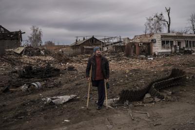 A resident stands next to parts of a destroyed Russian tank in the town of Trostsyanets, Ukraine, Monday, March 28, 2022. Trostsyanets was recently retaken by Ukrainian forces after being held by Russians since the early days of the war. (AP Photo/Felipe Dana)