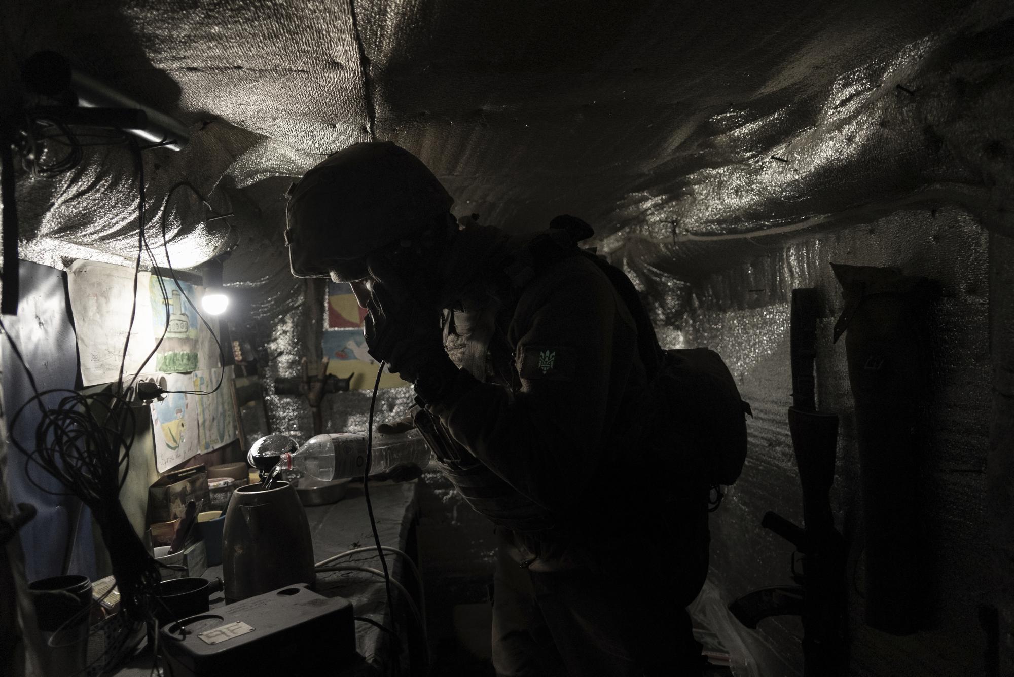 Zakhar Leshchyshyn, a Ukrainian serviceman, reports to a commander via military intercom while in a shelter at the frontline positions near Zolote, Ukraine, Saturday, Feb. 19, 2022. (AP Photo/Mstyslav Chernov)