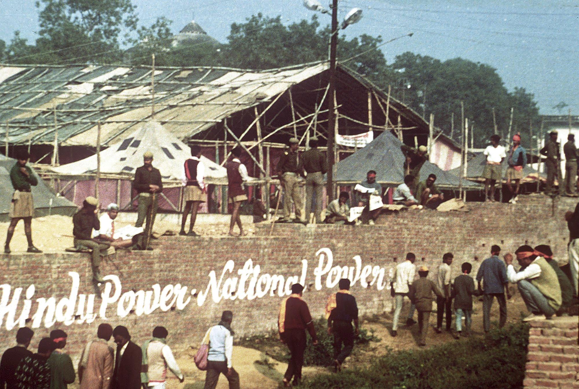 ARQUIVO - Fundamentalistas hindus caminham ao longo da parede do perímetro do disputado local de um templo de Ram a ser construído onde a mesquita Babri, atrás das árvores, ainda estava quando esta foto foi tirada em Ayodhya, 6 de dezembro de 1992. Mais tarde, militantes hindus invadiu a mesquita muçulmana de 430 anos e a destruiu. Em 2019, a Suprema Corte da Índia decidiu a favor da construção de um templo hindu no local disputado. Os hindus acreditam que seu deus Ram nasceu lá e dizem que o imperador muçulmano Babur construiu uma mesquita no topo de um templo no local. (Foto AP/Udo Weitz, Arquivo)