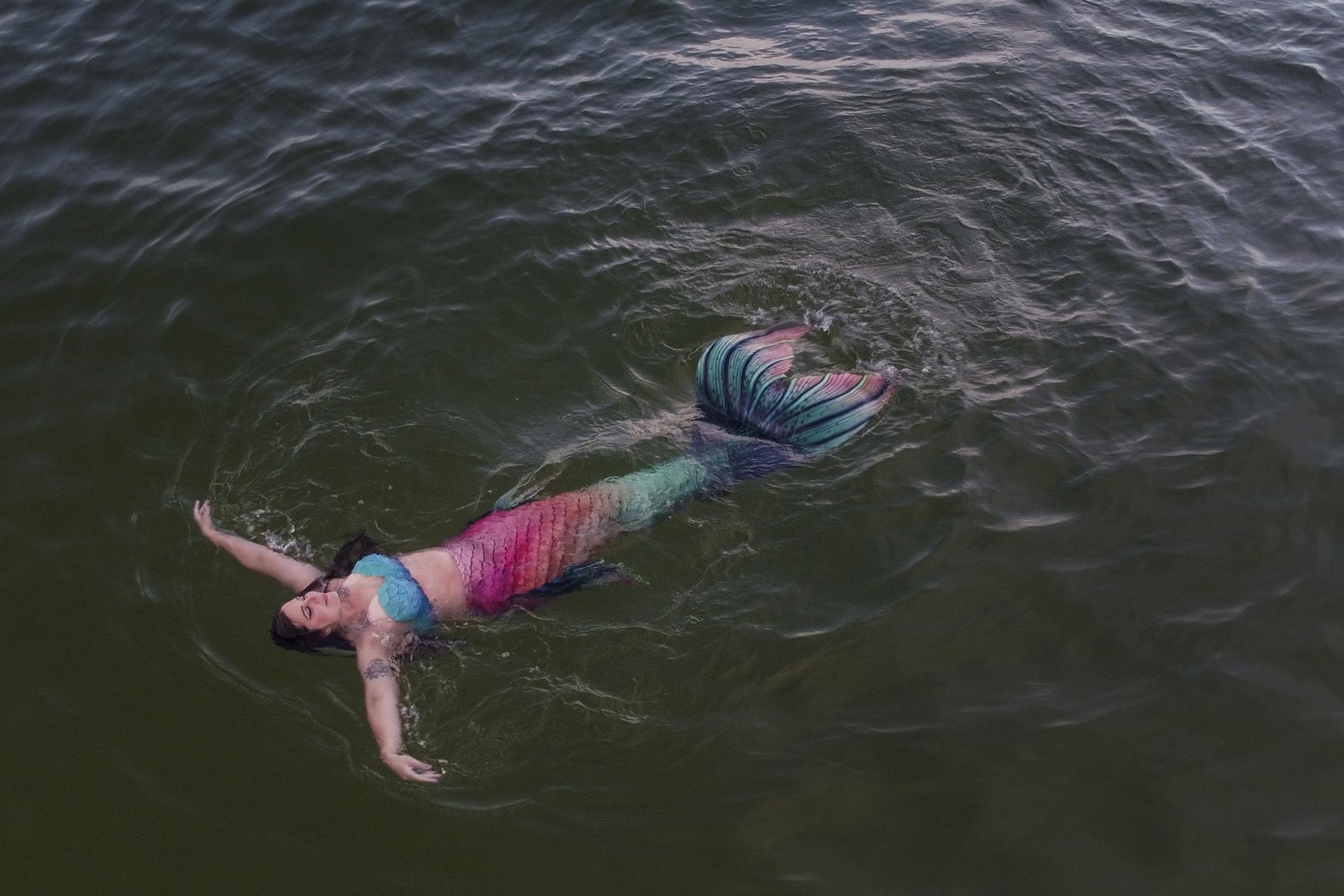 Lauren Metzler, founder of Sydney Mermaids, swims at Manly Cove Beach in Sydney, Australia, Thursday, May 26, 2022. "Some people have a coffee in the morning to wake up, some people have a mermaid swim," Metzler says with a laugh as she glides through the water, her skin adorned with sparkly sequins. "This tail is so fun to swim in!" (AP Photo/Mark Baker)