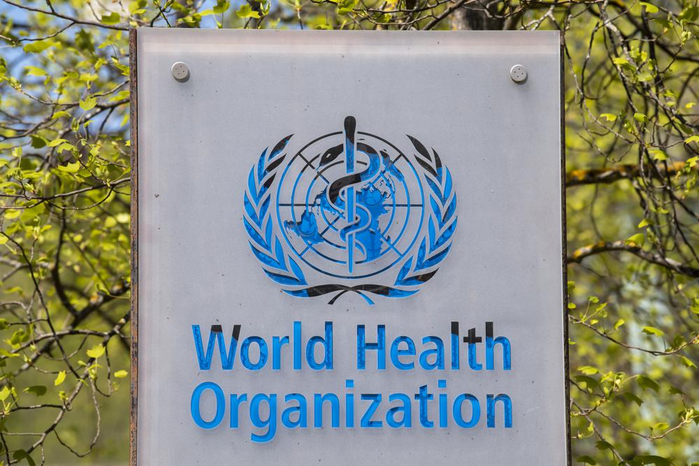 FILE - The logo and building of the World Health Organization (WHO) headquarters in Geneva, Switzerland, 15 April 2020. WHO said it’s creating a global training center to help poorer countries make vaccines, antibodies and cancer treatments using the messenger RNA technology used to make COVID-19 vaccines. At a press briefing Wednesday, Feb. 23, 2022 the U.N. health agency said the new hub will be based in South Korea and will share mRNA technology being developed by WHO and partners in South Africa, where scientists are already working to recreate the COVID-19 vaccine made by Moderna Inc. (Martial Trezzini/Keystone via AP, file)