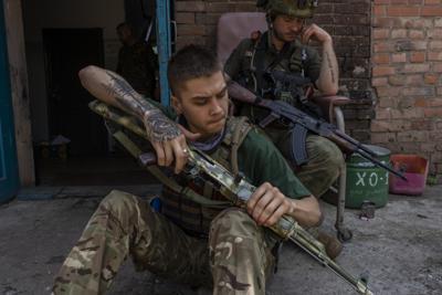 Un miembro de seguridad de un equipo de rescate médico limpia su arma en la región de Donetsk, en el este de Ucrania, el sábado 4 de junio de 2022. (AP Foto/Bernat Armangue)