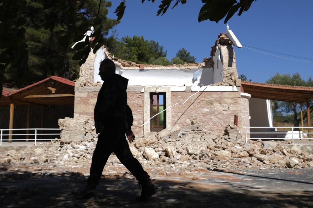 Ein Bewohner geht nach einem starken Erdbeben im Dorf Arcalochori auf der südlichen Insel Kreta, Griechenland, Montag, 27. September 2021, neben einer beschädigten griechisch-orthodoxen Kapelle vorbei. Ein starkes Erdbeben mit einer vorläufigen Stärke von 5,8 hat die südgriechische Insel Kreta und griechische Behörden sagen, dass eine Person getötet und mehrere weitere verletzt wurden. (AP-Foto/Harry Nikos)