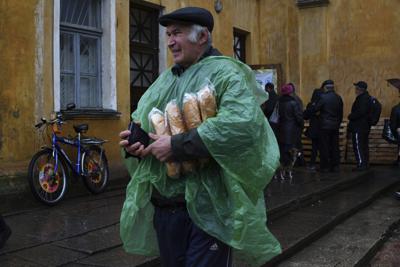 Un hombre lleva un pasaporte ucraniano y pan después de recibirlo en un centro de ayuda humanitaria en Kramatorsk, Ucrania, el 26 de octubre de 2022. (Foto AP/Andriy Andriyenko)