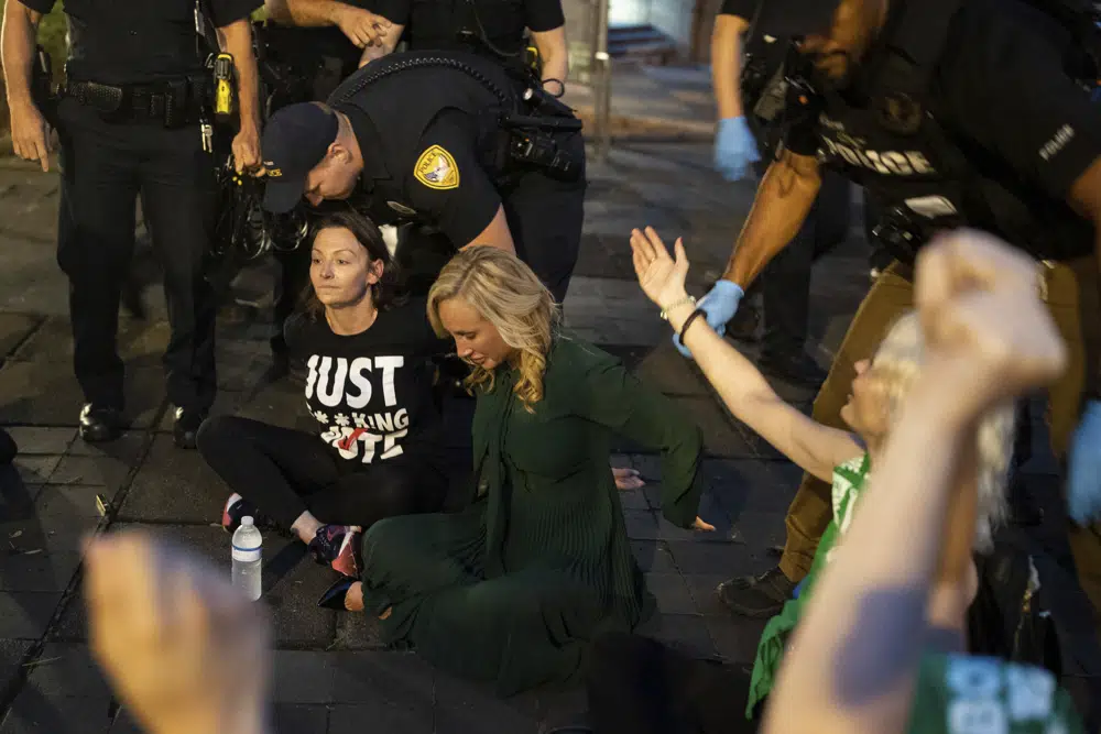 Sen. Lauren Book, seated right, along with Democratic Chairwoman Nikki Fried, seated left, and about a dozen activists who were protesting SB 300, which would place a ban on abortions after six weeks, are arrested outside the Tallahassee City Hall building, Monday, April 3, 2023, in Tallahassee, Fla. (Alicia Devine/Tallahassee Democrat via AP)