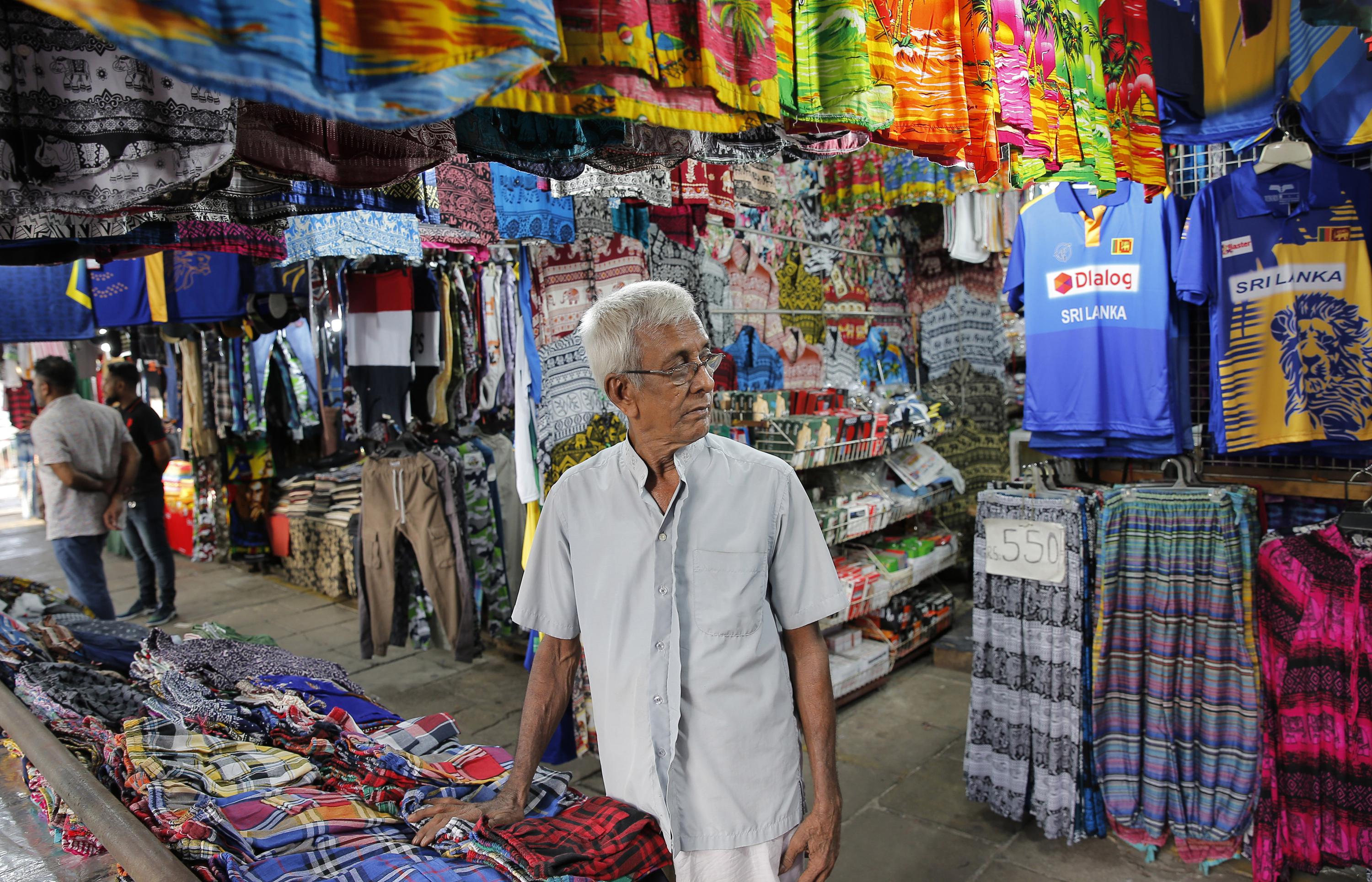 Sri Lankans walk on a deserted street at a wholesale market during