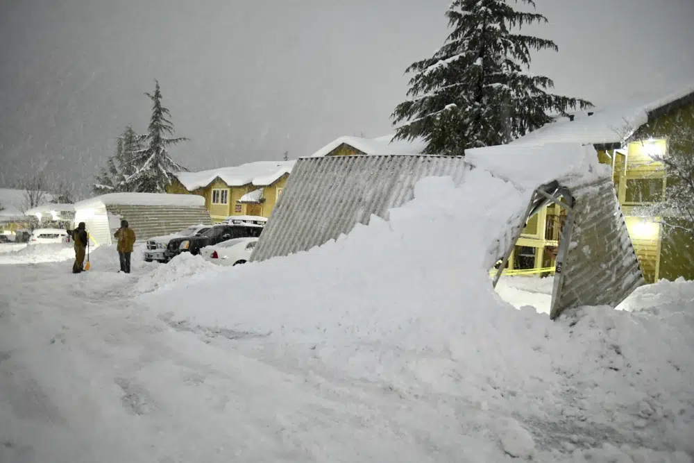 Un par de residentes en los apartamentos de Cedar Park en Grass Valley, California, toman un descanso de palear nieve durante las condiciones de ventisca del martes por la noche el 28 de febrero de 2023, que causaron daños generalizados en Sierra Nevada, incluidos estos toldos, que se doblaron desde la nieve.  (Elias Funez/La Unión vía AP)