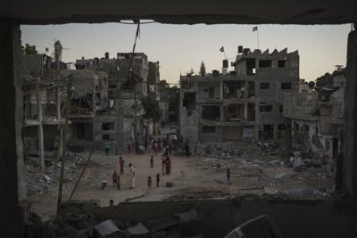 Palestinos caminando por la calle Al-Baali, junto a las ruinas de casas dañadas por ataques aéreos en la guerra de 11 días entre Israel y Hamas, el grupo armado que controla Gaza, en Beit Hanoun, en el norte de la Franja de Gaza, el miércoles 16 de junio de 2021. Desde 2008, más de 4.000 palestinos han muerto en cuatro guerras, según Naciones Unidas. (AP Foto/Felipe Dana)