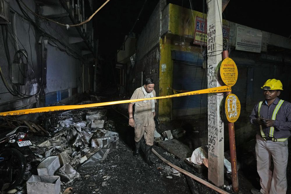 A fire official returns after controlling a fire in a four storied building, in New Delhi, India, Saturday, May 14, 2022. A massive fire erupted in a four-storied building in the Indian capital on Friday, killing at least 19 people and leaving several injured, the fire control room said. Dozens of people have been rescued from the commercial building, mainly shops, in the Mundka area in the western part of New Delhi. (AP Photo/Manish Swarup)