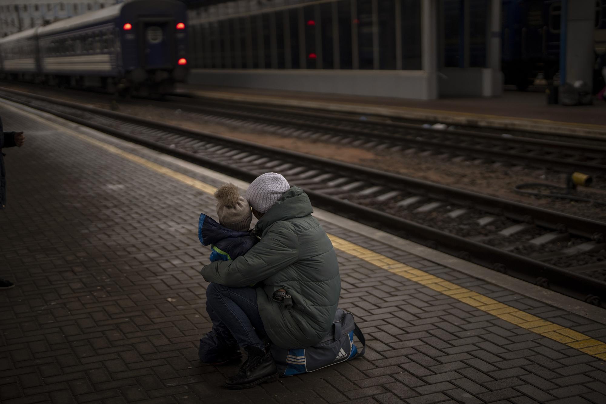 A woman with her son look at a train leaving as they try to flee at the Kyiv station, Ukraine, Thursday, March 3. 2022. (AP Photo/Emilio Morenatti)