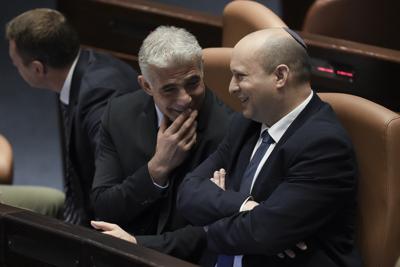 El primer ministro de Israel, Naftali Bennett (derecha), y el ministro de Exteriores, Yair Lapid, hablan antes de una votación para disolver el parlamento, en el Knesset, en Jerusalén, el 30 de junio de 2022. (AP Foto/Ariel Schalit)