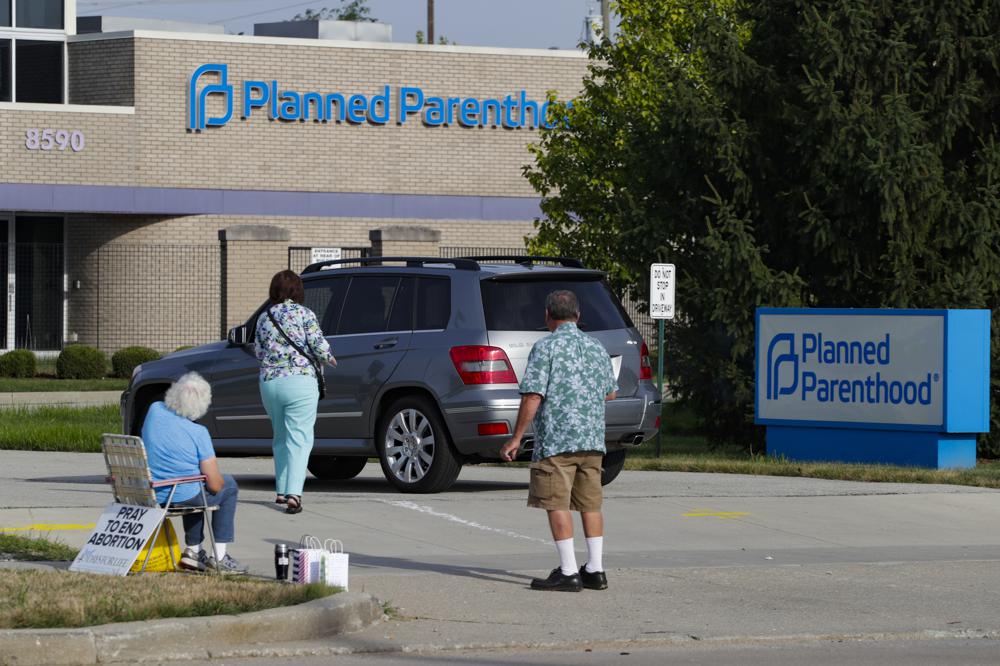 FILE - In this Aug. 16, 2019 file photo, abortion protesters attempt to handout literature as they stand in the driveway of a Planned Parenthood clinic in Indianapolis. A federal appeals court has cleared the way for Indiana officials to start enforcing a law requiring reports from doctors if they treat women for complications arising from abortions, even though the court said the law could be struck down in the future. Action by the 7th Circuit Court of Appeals this week followed a 2-1 ruling by a court panel in August upholding the law, which had been blocked by a judge shortly after it was approved by the Republican-dominated Indiana Legislature in 2018. (AP Photo/Michael Conroy File)