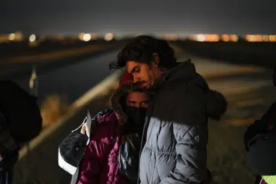 Cuban migrant Mario Perez holds his wife as they wait to be processed to seek asylum after crossing the border into the United States, Friday, Jan. 6, 2023, near Yuma, Ariz. President Joe Biden says the U.S. will immediately begin turning away Cubans, Haitians and Nicaraguans who cross the border from Mexico illegally. It's his boldest move yet to confront spiraling arrivals of migrants since he took office two years ago. (AP Photo/Gregory Bull)