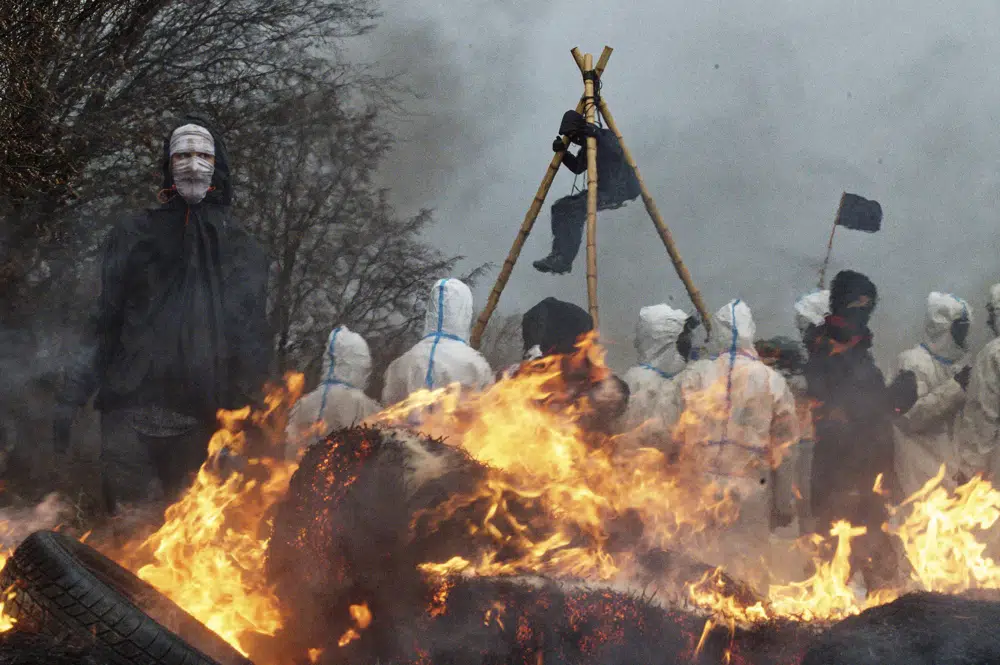 Activists build barricades and set them on fire while the police make preparations for the planned eviction of the village Luetzerath, western Germany, Monday, Jan. 2, 2023. The village of Luetzerath has to be demolished to expand the Garzweiler lignite coal mine near the dutch border. (Henning Kaiser/dpa via AP)