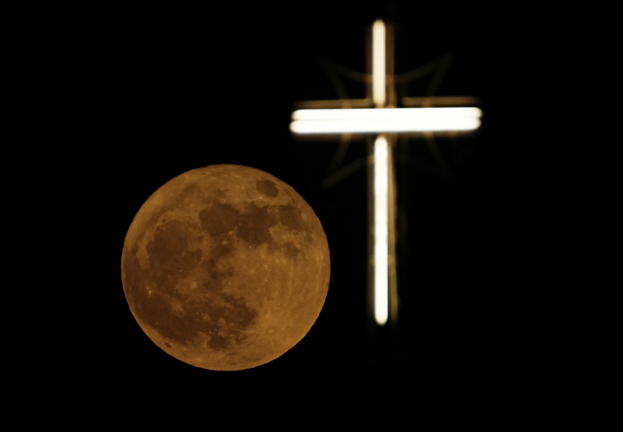 A lua cheia nasce sobre a cruz da Igreja de São José em Bagdá, Iraque, terça-feira, 14 de junho de 2022. . (AP/Foto/Hadi Mizban)