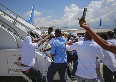 Haitianos deportados de Estados Unidos tratan de subir al mismo avión en el que viajaron su país de origen, en el Aeropuerto Toussaint Louverture, en Puerto Príncipe, Haití, el martes 21 de septiembre de 2021. (AP Foto/Joseph Odelyn)