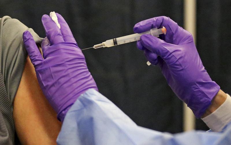 FILE - A man gets a COVID-19 vaccine at a mass vaccination site at the Natick Mall on Wednesday, Feb. 24, 2021, in Natick, Mass.  U.S. experts are expected to recommend COVID-19 vaccine boosters for all Americans, regardless of age, eight months after they received their second dose of the shot, to ensure lasting protection against the coronavirus as the delta variant spreads across the country. An announcement was expected as soon as this week, with doses beginning to be administered widely once the Food and Drug Administration formally approves the vaccines. (Matt Stone/The Boston Herald via AP, Pool)