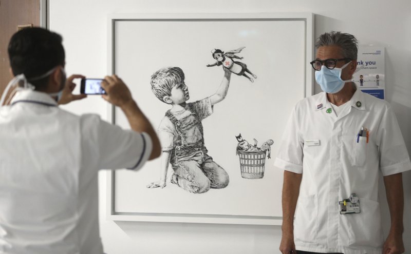 Un membre del personal sanitari es fotografia davant de l’obra de Banksy