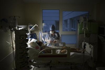 Una enfermera atiende a un enfermo con COVID-19 que recibe apoyo de un respirador en la Unidad de Cuidados Intensivos del hospital la Timone en Marsella, Francia, el viernes 31 de diciembre de 2021. (AP Foto/Daniel Cole)