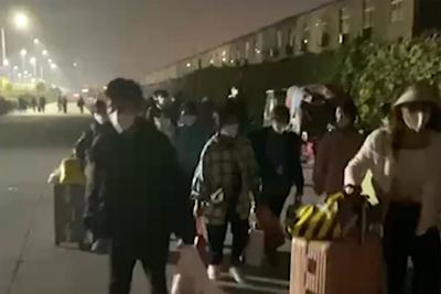 En esta imagen extraída de un video y publicada por Hangpai Xingyang, gente con maletas sale de un complejo de Foxconn en Zhengzhou, en la provincia central china de Henan, el sábado 29 de octubre de 2022. Los trabajadores en una planta de Foxconn en la ciudad central china de Zhengzhou parecían haber abandonado el recinto para evitar restricciones asociadas al COVID-19. (Hangpai Xingyang vía AP)