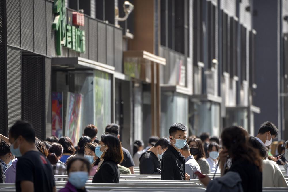 Personas con mascarillas hacen fila para hacerse pruebas de coronavirus en un vecindario del distrito Dongcheng de Beijing, el martes 26 de abril de 2022. Beijing realizará pruebas masivas a la mayoría de sus 21 millones de habitantes, anunciaron las autoridades el lunes, como un nuevo brote de COVID-19 El brote provocó el almacenamiento de alimentos por parte de los residentes preocupados por la posibilidad de un cierre al estilo de Shanghái.  (Foto AP/Mark Schiefelbein)