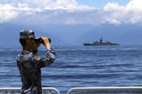 FILE - In this photo provided by China's Xinhua News Agency, a People's Liberation Army member looks through binoculars during military exercises as Taiwan's frigate Lan Yang is seen at the rear on Aug. 5, 2022. China on Wednesday, Aug. 10, reaffirmed its threat to use military force to bring self-governing Taiwan under its control, amid threatening Chinese military exercises that have raised tensions between the sides to their highest level in years. (Lin Jian/Xinhua via AP, File)