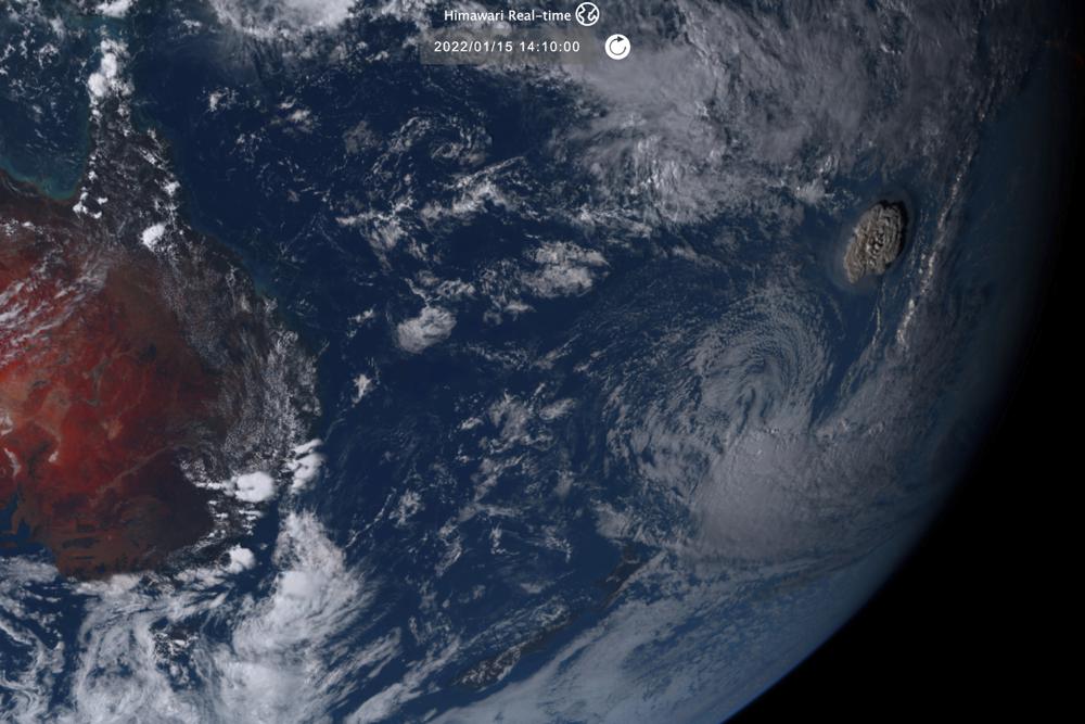 Citra satelit yang diambil oleh Himawari-8, satelit cuaca Jepang yang dioperasikan oleh Badan Meteorologi Jepang dan dirilis oleh Institut Teknologi Informasi dan Komunikasi Nasional (NICT), menunjukkan letusan gunung berapi bawah laut, kanan, di negara Pasifik Tonga, Sabtu, 1 Januari. 15, 2022. (NICT melalui AP)