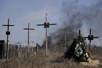 Un humo de los bombardeos se eleva cuando se coloca una corona de flores en un cementerio en Vasylkiv, al suroeste de Kiev, Ucrania, el sábado 12 de marzo de 2022. Las fuerzas rusas parecían progresar desde el noreste de Ucrania en su lenta lucha para llegar a la capital, Kiev, mientras que los tanques y la artillería golpeaban lugares ya sitiados. (AP Foto/Vadim Ghirda)