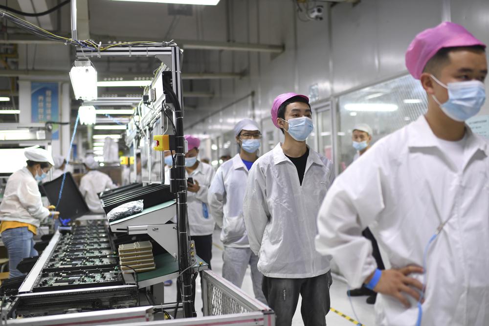 ARCHIVO - Trabajadores se forman para someterse a una prueba de coronavirus en una fábrica de Wuhan, China, el 5 de agosto de 2021. (Chinatopix vía AP, Archivo)